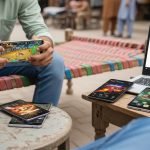 A man plays a game on his laptop, surrounded by several people engaged in the activity around him. Most Downloaded APK Games